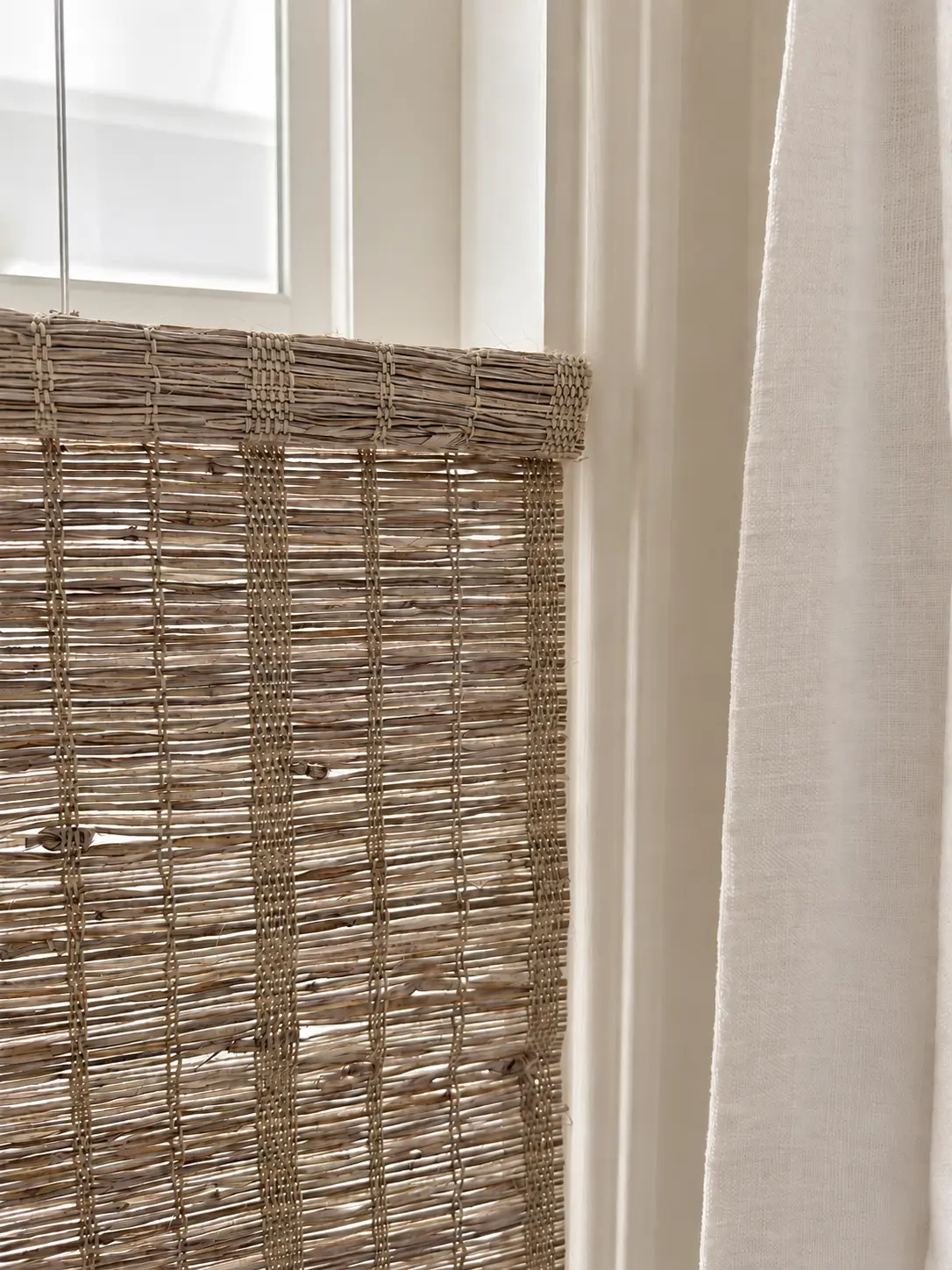 Installed Sandy Fawn weave with irregular horizontal fibers and fine vertical binding threads beside white drapery